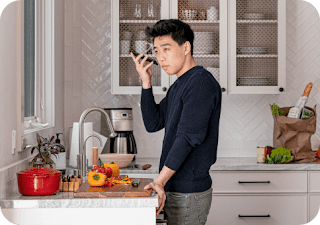 Un homme asio-américain se tient près d'un plan de travail dans une cuisine. Il tient son téléphone Android et écoute le lecteur d'écran énoncer une recette.