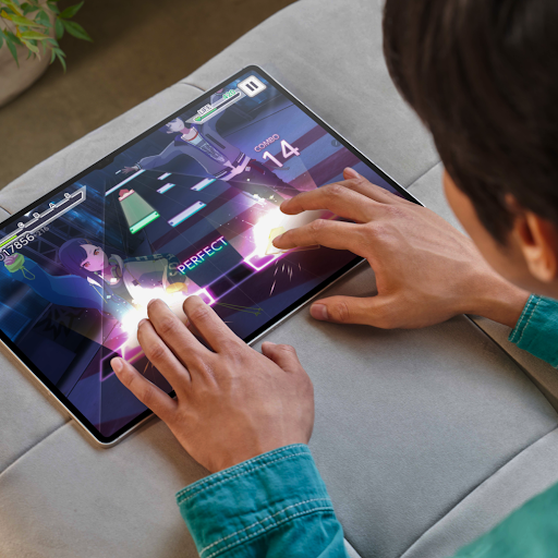 A person playing an online game on a tablet, with the large screen displaying gaming characters, the score and cinematic visuals.