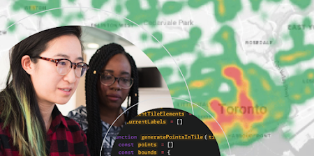 Two people writing code on a computer over a heatmap.
