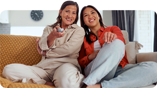 Mother and daughter watching Google TV and holding a remote.